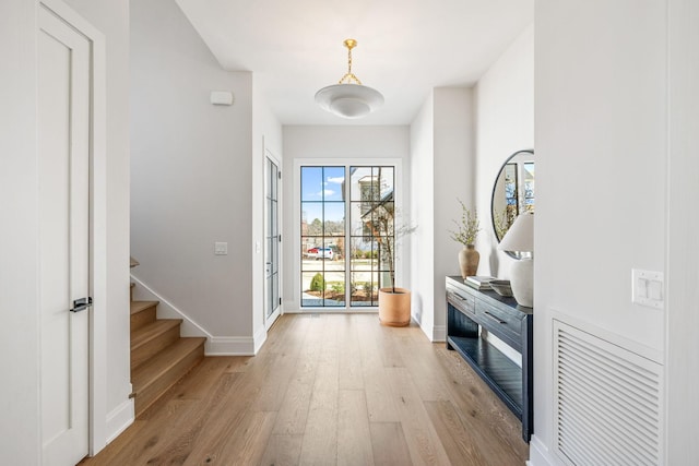 entryway with light wood finished floors, stairs, and baseboards