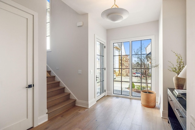 doorway to outside with baseboards, stairway, and wood finished floors