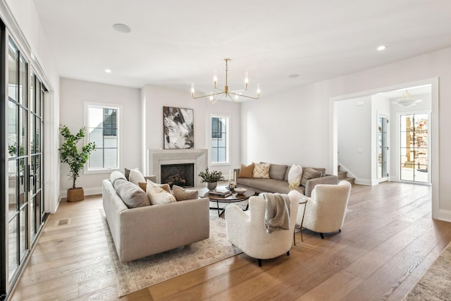 living room with a chandelier, recessed lighting, a fireplace, and light wood-style floors