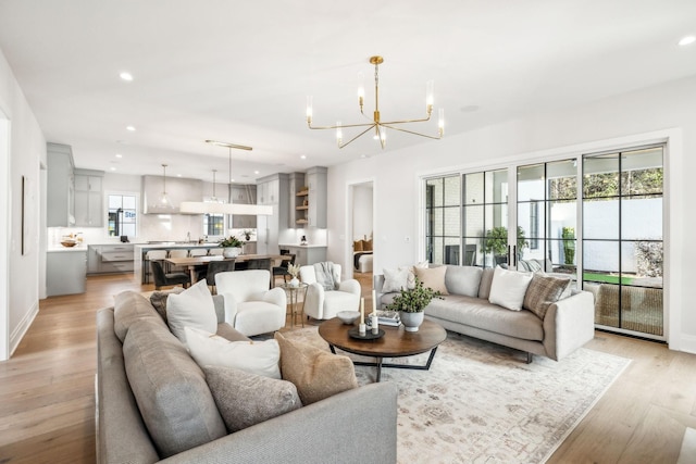 living area featuring a chandelier, light wood-type flooring, baseboards, and recessed lighting