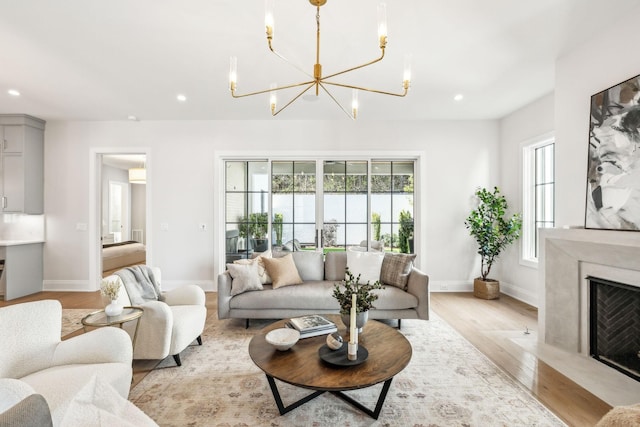 living room with recessed lighting, light wood-style flooring, baseboards, and a high end fireplace