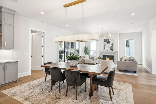 dining room with light wood-style floors, a fireplace, baseboards, and recessed lighting