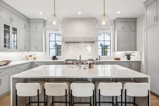 kitchen featuring light wood finished floors, premium range hood, gray cabinets, and backsplash