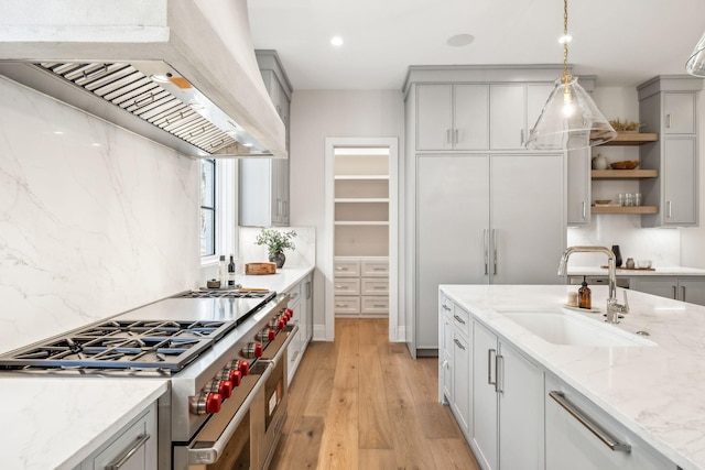 kitchen featuring range with two ovens, premium range hood, a sink, gray cabinets, and open shelves