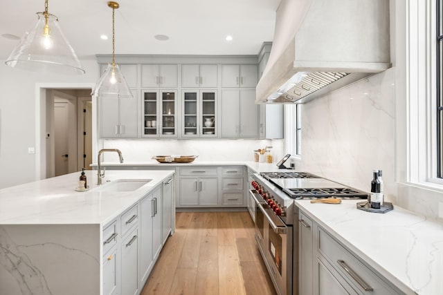 kitchen with light wood-type flooring, premium range hood, range with two ovens, and decorative backsplash