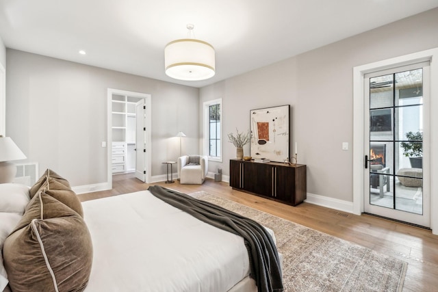 bedroom featuring access to exterior, visible vents, baseboards, and wood finished floors