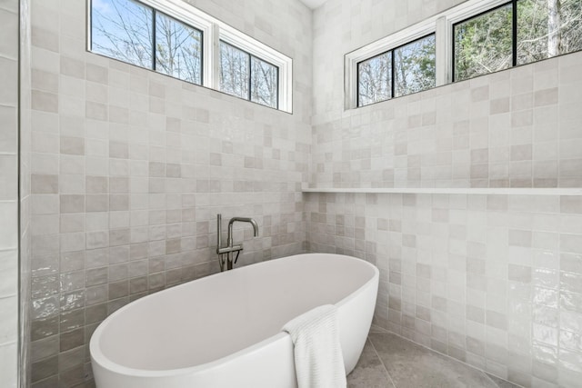 full bathroom with a freestanding bath, tile patterned flooring, and tile walls