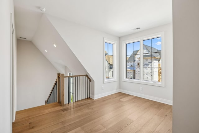 spare room featuring lofted ceiling, wood finished floors, visible vents, and baseboards