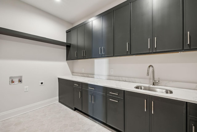 kitchen featuring baseboards, light stone countertops, dark cabinetry, a sink, and light tile patterned flooring