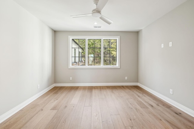 spare room with visible vents, light wood finished floors, a ceiling fan, and baseboards