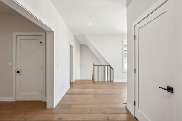 corridor with light wood-style floors, baseboards, and recessed lighting