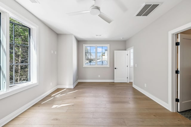 empty room featuring baseboards, plenty of natural light, visible vents, and light wood-style floors