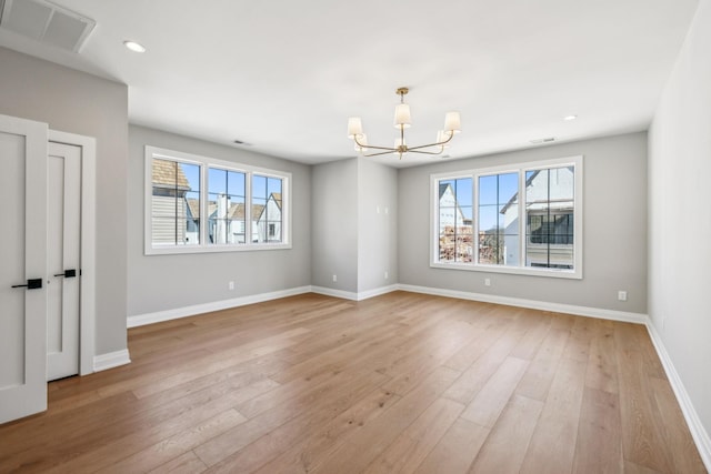 unfurnished room featuring light wood-style flooring, visible vents, a chandelier, and baseboards