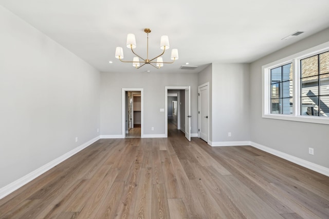 interior space featuring visible vents, baseboards, a notable chandelier, and wood finished floors