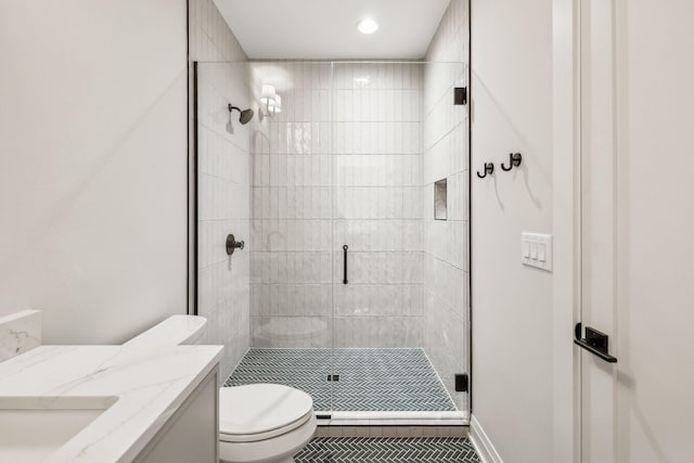 bathroom featuring toilet, a stall shower, baseboards, and vanity