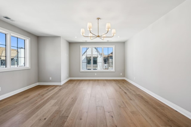 unfurnished dining area featuring baseboards, a notable chandelier, visible vents, and light wood finished floors