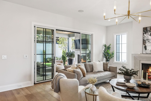 living area featuring a notable chandelier, recessed lighting, a premium fireplace, wood finished floors, and baseboards