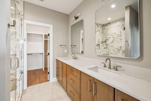 full bathroom featuring double vanity, a shower stall, and a sink