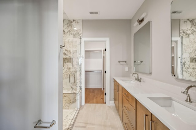 bathroom with a shower stall, visible vents, and a sink