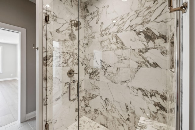 full bath with a marble finish shower and baseboards