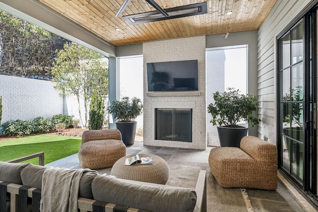 sunroom / solarium featuring an outdoor brick fireplace and wooden ceiling