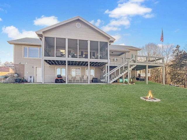 back of property featuring a patio area, a sunroom, an outdoor fire pit, a yard, and a deck