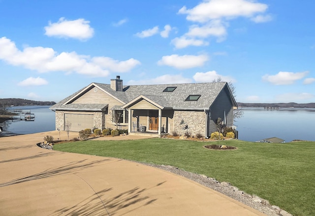 view of front of property with a front lawn, a garage, and a water view