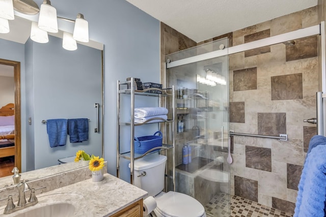 bathroom with a textured ceiling, toilet, a shower with shower door, and vanity