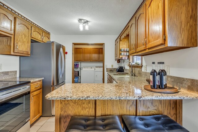 kitchen featuring a kitchen bar, kitchen peninsula, and independent washer and dryer