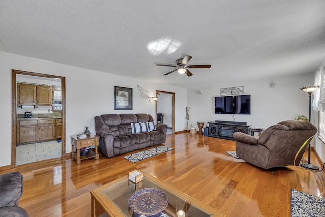 living room featuring a textured ceiling, light hardwood / wood-style flooring, and ceiling fan