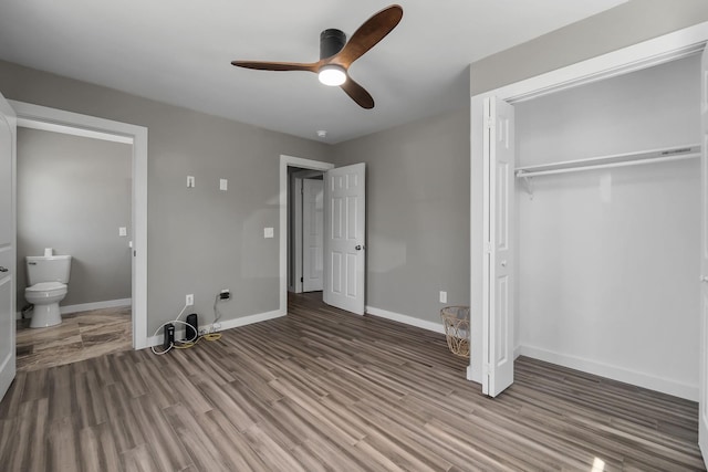 unfurnished bedroom with a closet, connected bathroom, wood-type flooring, and ceiling fan