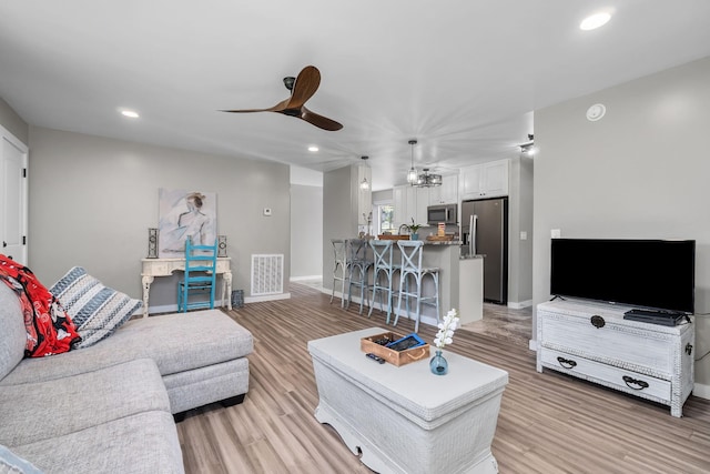 living room with ceiling fan, sink, and light hardwood / wood-style floors