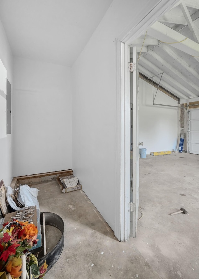 interior space featuring lofted ceiling, concrete flooring, and electric panel