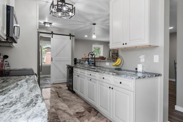 kitchen featuring white cabinetry, sink, hanging light fixtures, and a barn door