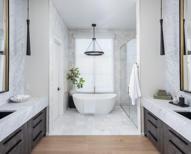 bathroom with wood-type flooring, tile walls, vanity, and independent shower and bath