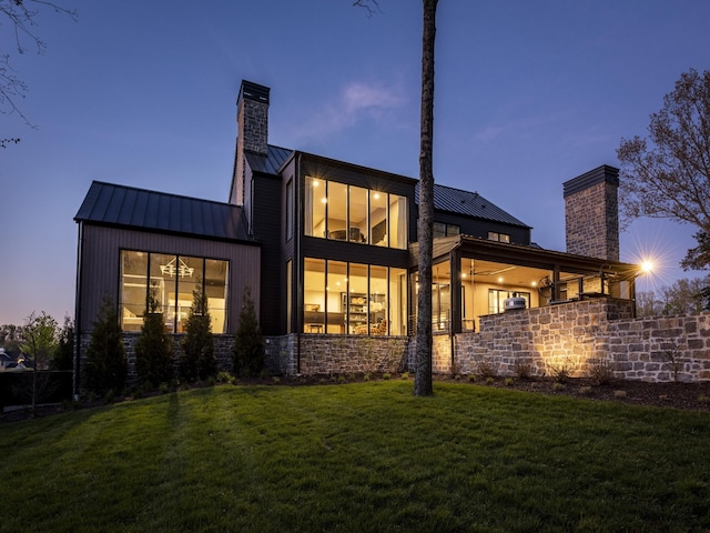 back house at dusk with a lawn