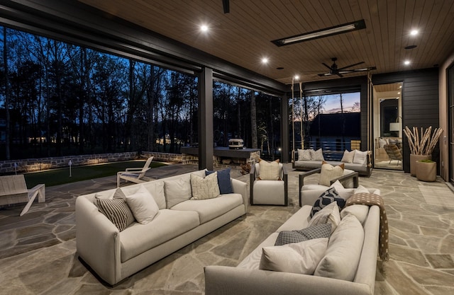 patio terrace at dusk with ceiling fan, a water view, and outdoor lounge area