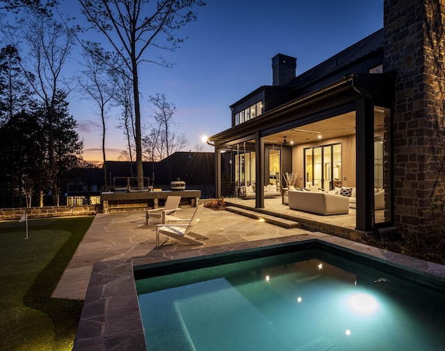 pool at dusk with an outdoor hangout area, ceiling fan, and a patio