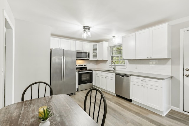 kitchen with decorative backsplash, sink, white cabinetry, light hardwood / wood-style flooring, and stainless steel appliances