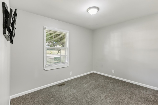 spare room featuring dark colored carpet