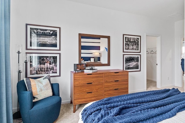 bedroom featuring light colored carpet and a walk in closet