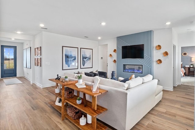 living room featuring light wood-type flooring and a large fireplace