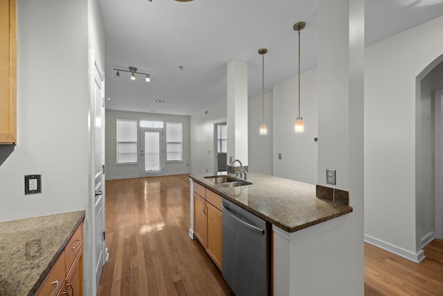 kitchen featuring hardwood / wood-style floors, decorative light fixtures, dishwasher, dark stone counters, and sink