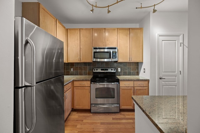 kitchen with appliances with stainless steel finishes, decorative backsplash, light brown cabinets, light hardwood / wood-style flooring, and light stone counters