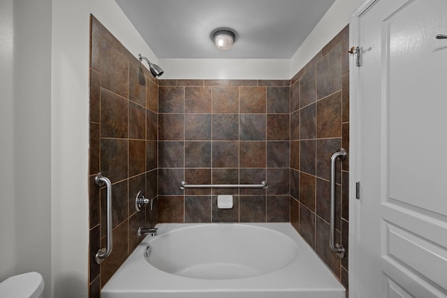 bathroom featuring toilet and tiled shower / bath