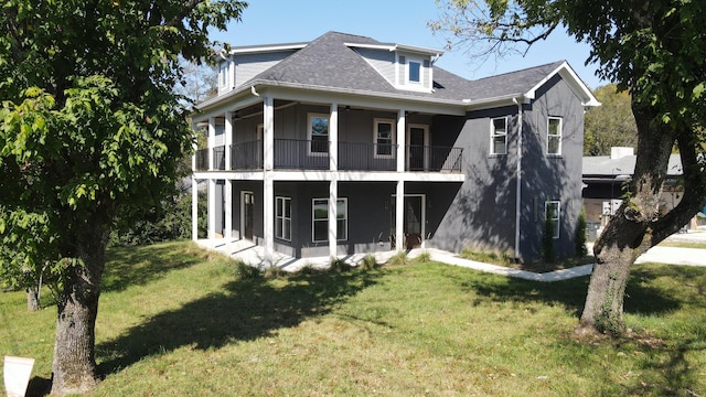 rear view of house featuring a lawn and a balcony