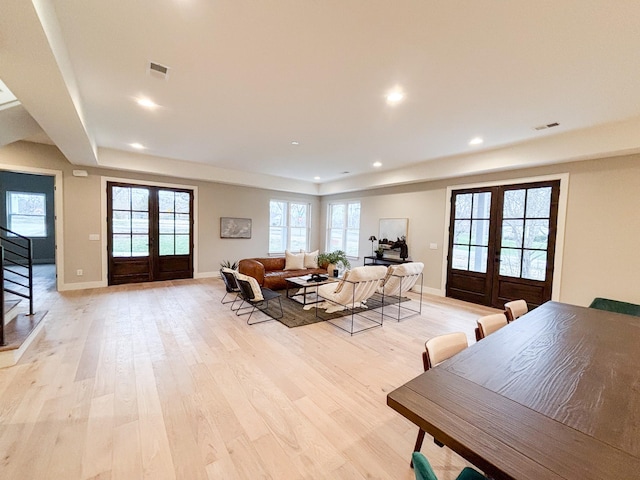 living room featuring french doors, stairway, visible vents, and light wood-style floors