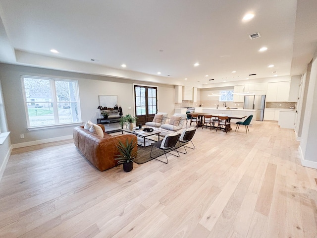 living room featuring baseboards, light wood-style flooring, visible vents, and recessed lighting