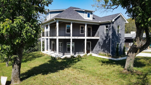 back of house with brick siding, a lawn, and a balcony