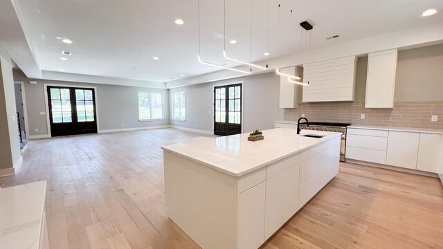 kitchen featuring a sink, light wood-style floors, french doors, decorative backsplash, and modern cabinets